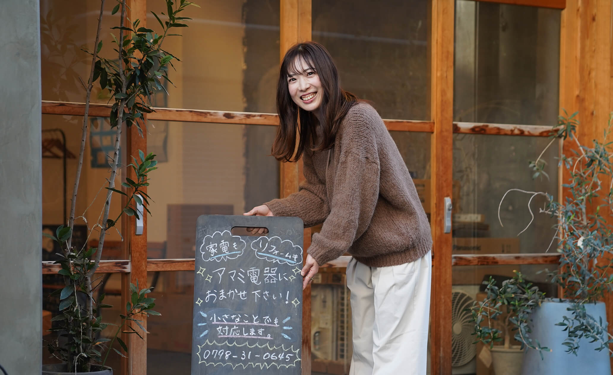 笑顔で立て看板を見せているスタッフの写真