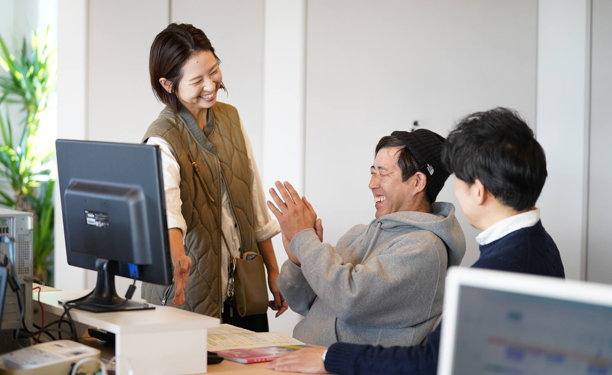 パソコンの前で話をする笑顔のスタッフ達の写真