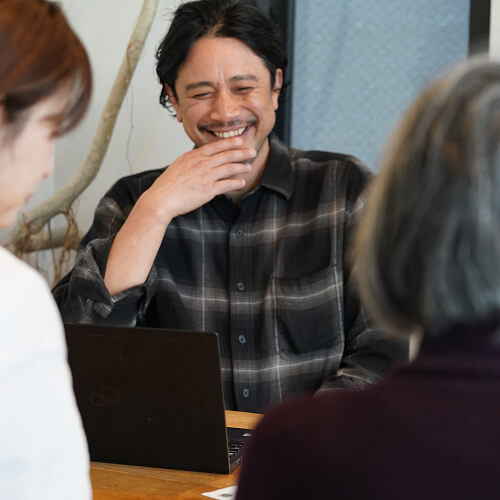 座ってお客様と話をする笑顔のスタッフの写真