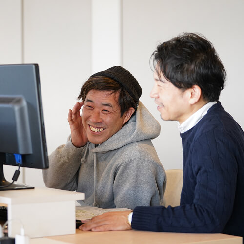 パソコンを前に笑顔で話すスタッフ達の写真