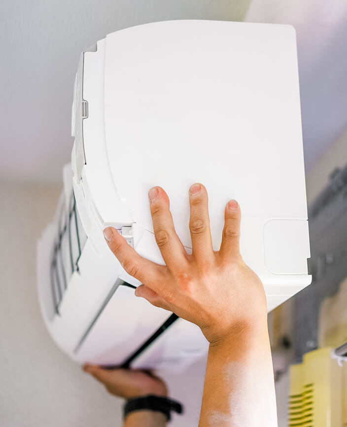 エアコンを下から両手で支えている写真