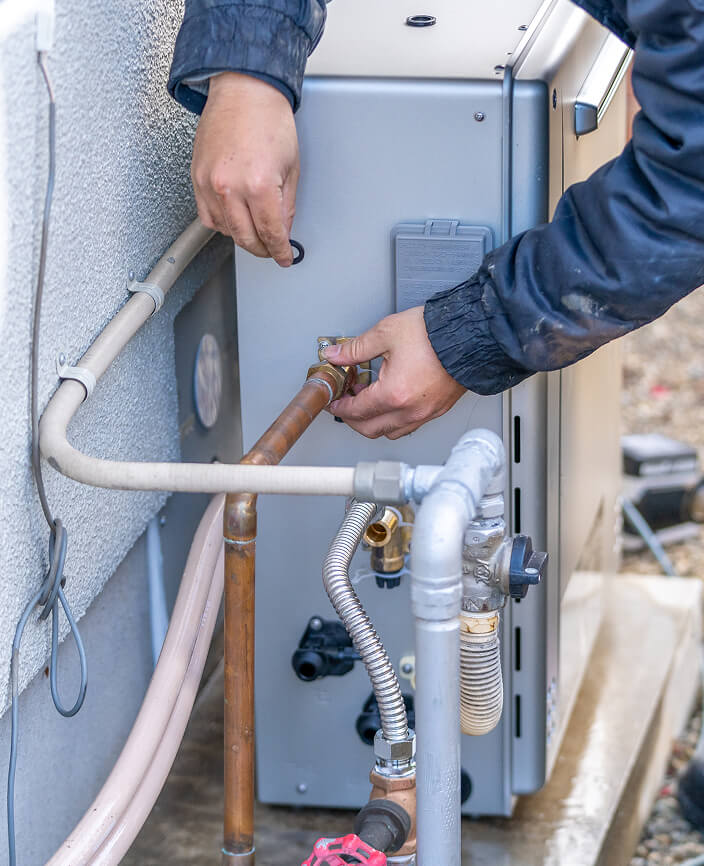 住宅の外にあるガス給湯器の作業をする手元の写真