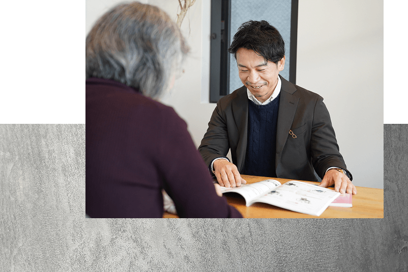 笑顔でパンフレットを見せながらお客様に説明をするスタッフの写真